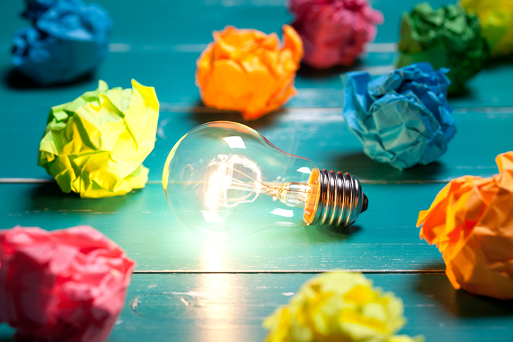 Incandescent bulb and colorful notes on turquoise wooden table. This file is cleaned and retouched.