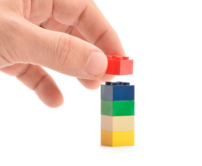 Ankara, Turkey - April 09, 2013: Hand putting Lego blocks to be assembled isolated on white background