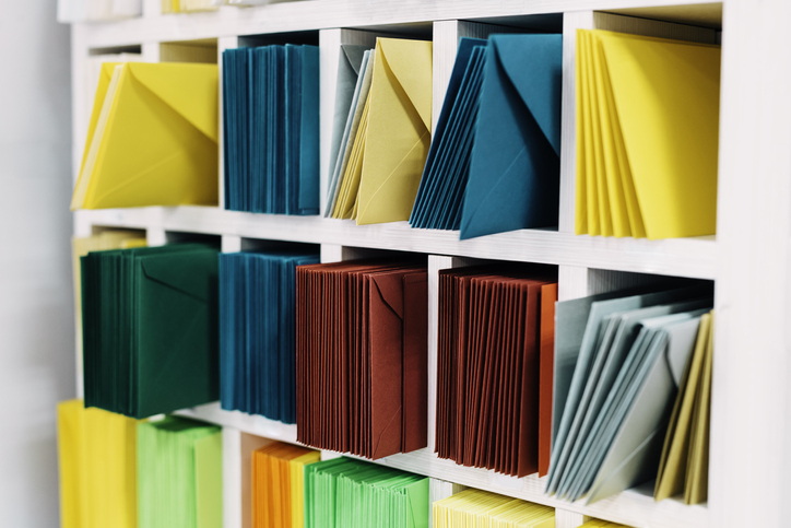 Various sort mail envelopes arranged on a shelf by color and type categories.